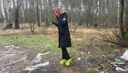A girl in very high heels went for a walk on a bad road made of ice and slippery mud, her shoes are clearly not designed for this road