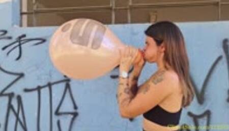 Maya Blows to Pop Two Printed Balloons