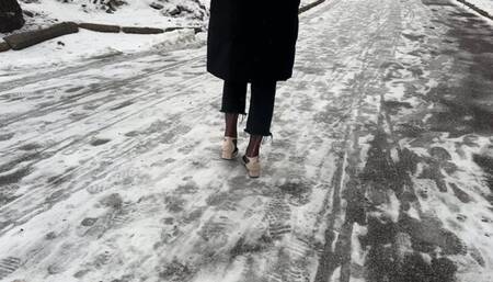 A girl in high heels wants to get to the road, but her path lies over a slippery hill