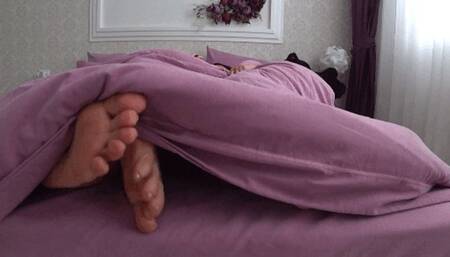 2 pairs of feet from under the blanket and toe play c