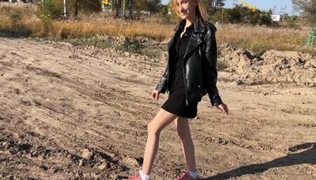 A girl in sneakers and white socks walks deep in the mud, she takes off her sneakers so that her snow-white socks turn brown