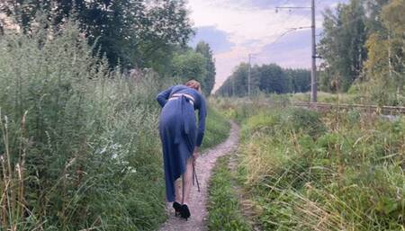 A girl walks in the park in high-heeled shoes and talks on the phone, she is so engrossed in the conversation that she does not notice where she steps on her heels