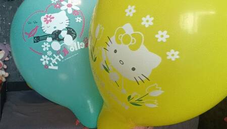 girl in swimsuit play with hello kitty balloons
